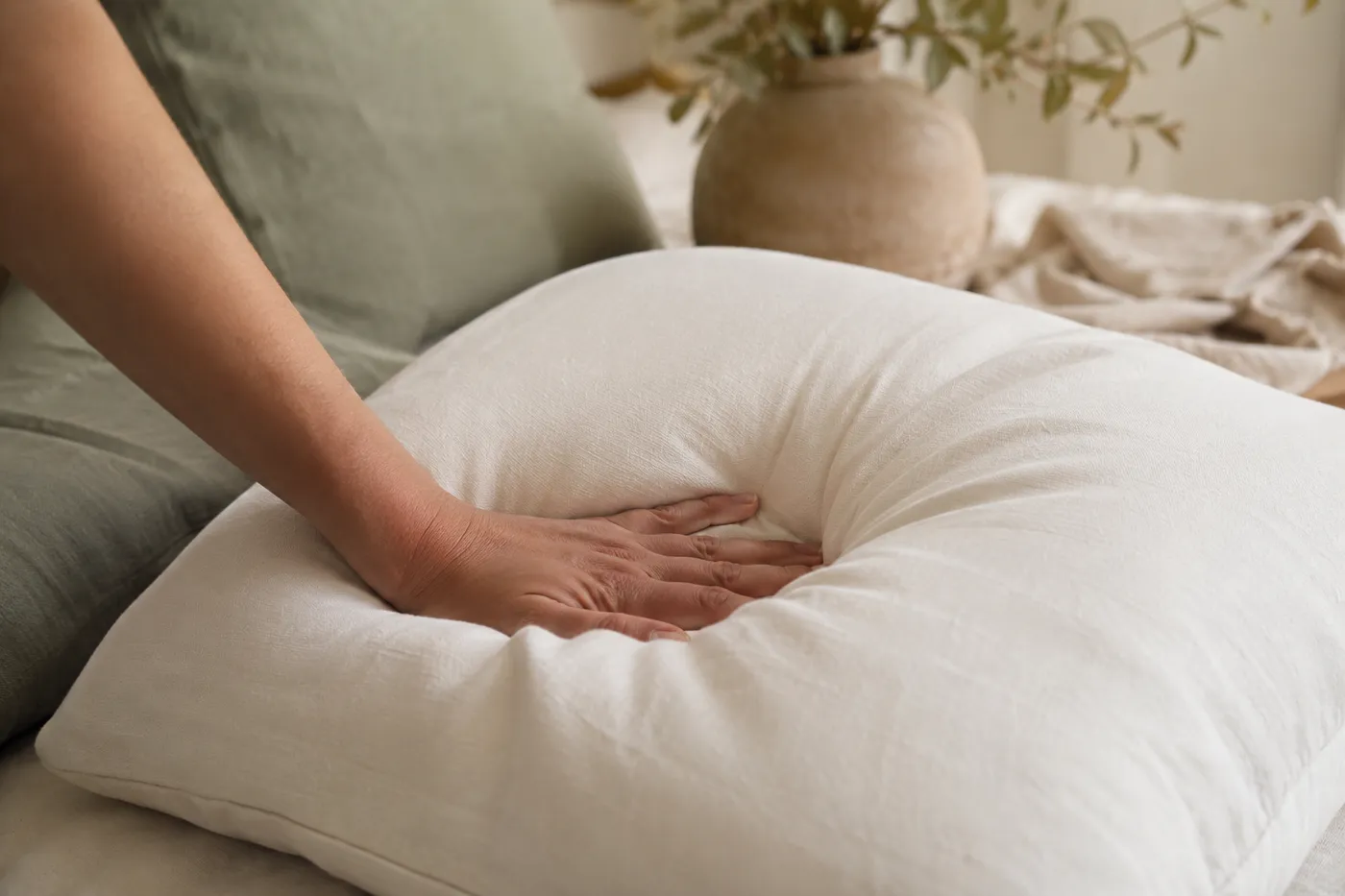 Hand pressing into an ultra-soft pillow showing its plush support
